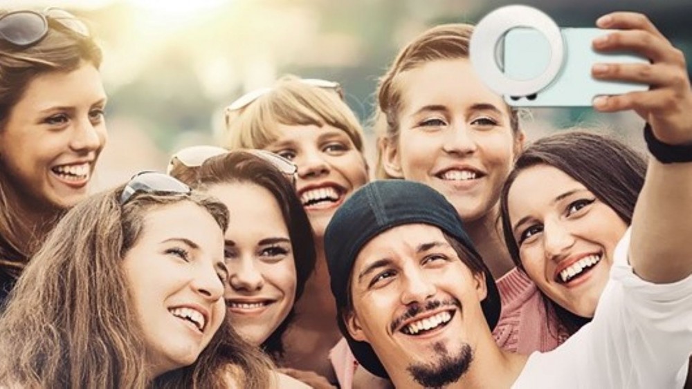 A group of friends taking a selfie with the QIAYA Ring Light on the phone.